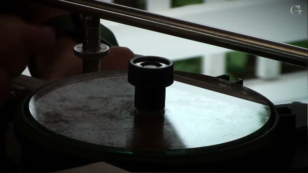 Worn grey disc still on the machine, lit hard from one side only