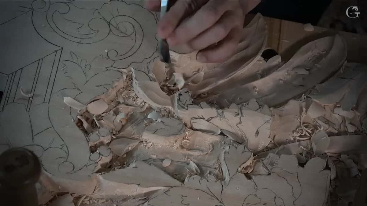A hand works a small gouge into the hollow while a mallet waits in the corner of the picture