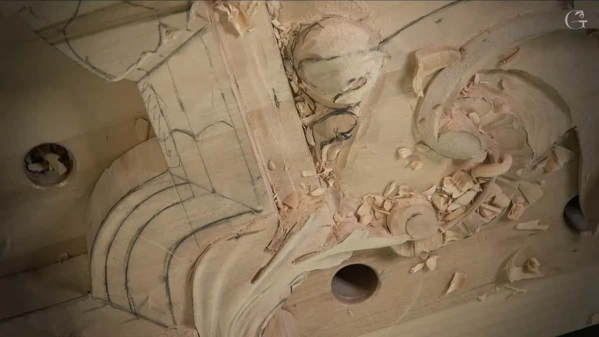 Close view of a molding in progress, with its lines drawn across the wood and a drill hole in the ground