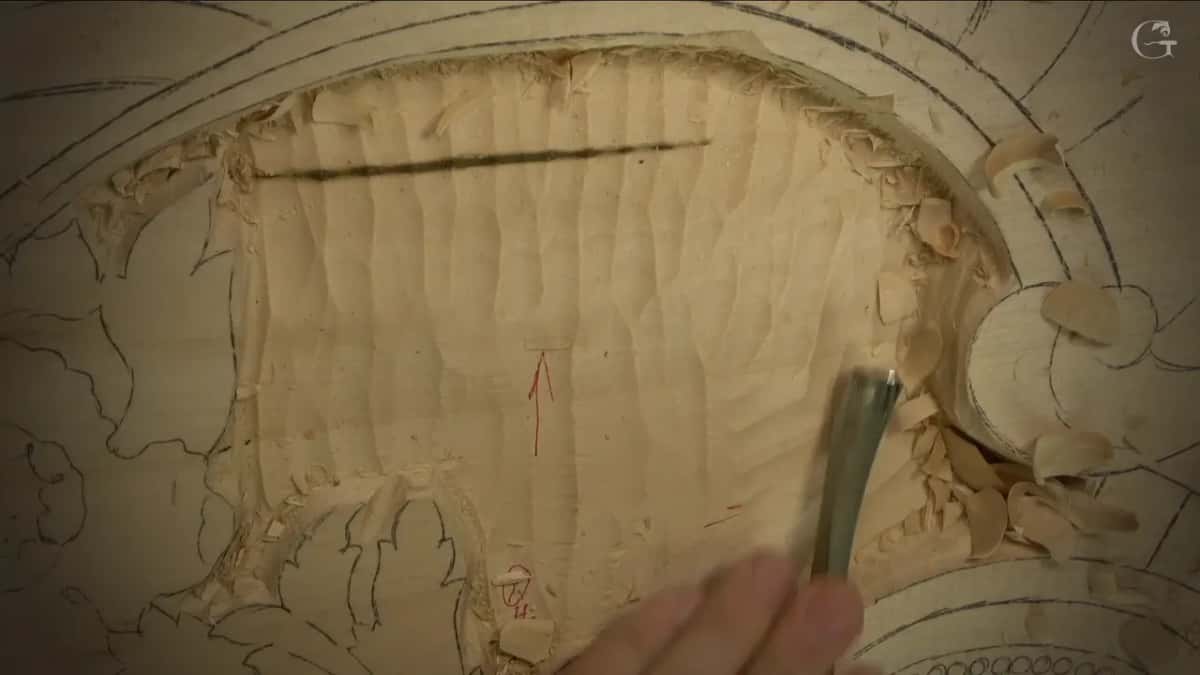 Ridges left by the gouge run down the field under a pencil line, a gouge held at its lower edge.