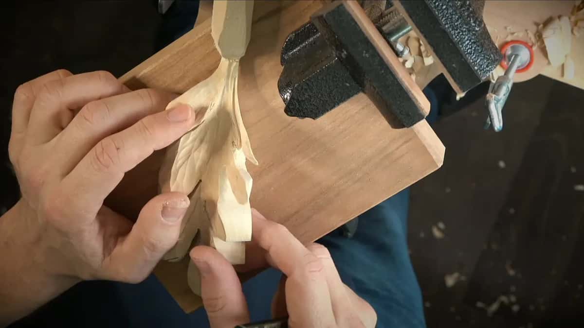 The mend Holding the carved leaf layer against the dark board, a clamp waiting behind