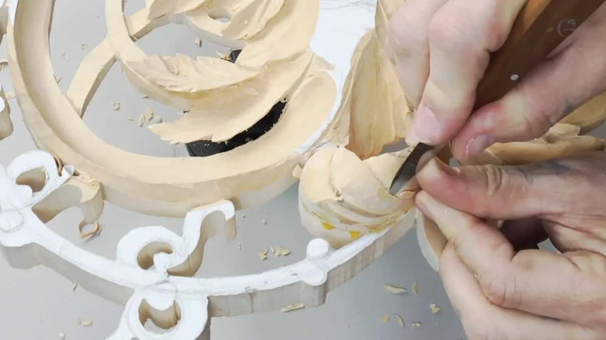Both hands guide a short wood handled blade into a round bud by the white border