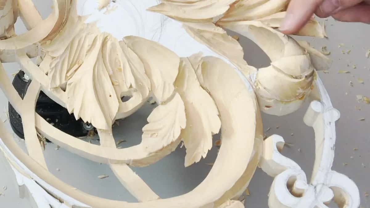 Fingertips on a leaf at the top right, a scroll and the stand below