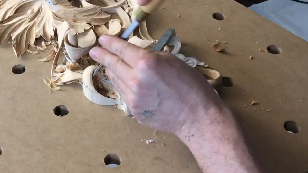Tattooed hand from the right, narrow tool pointing down