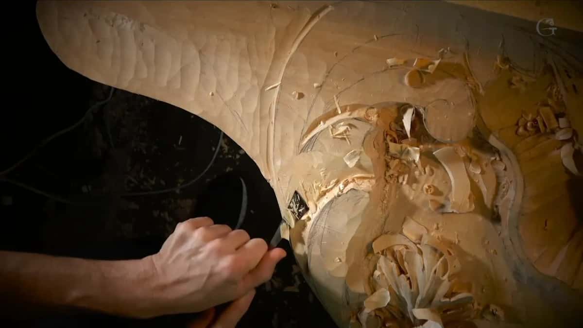 Seen from overhead, the curved end of the board runs off into darkness while one hand works a single spot.