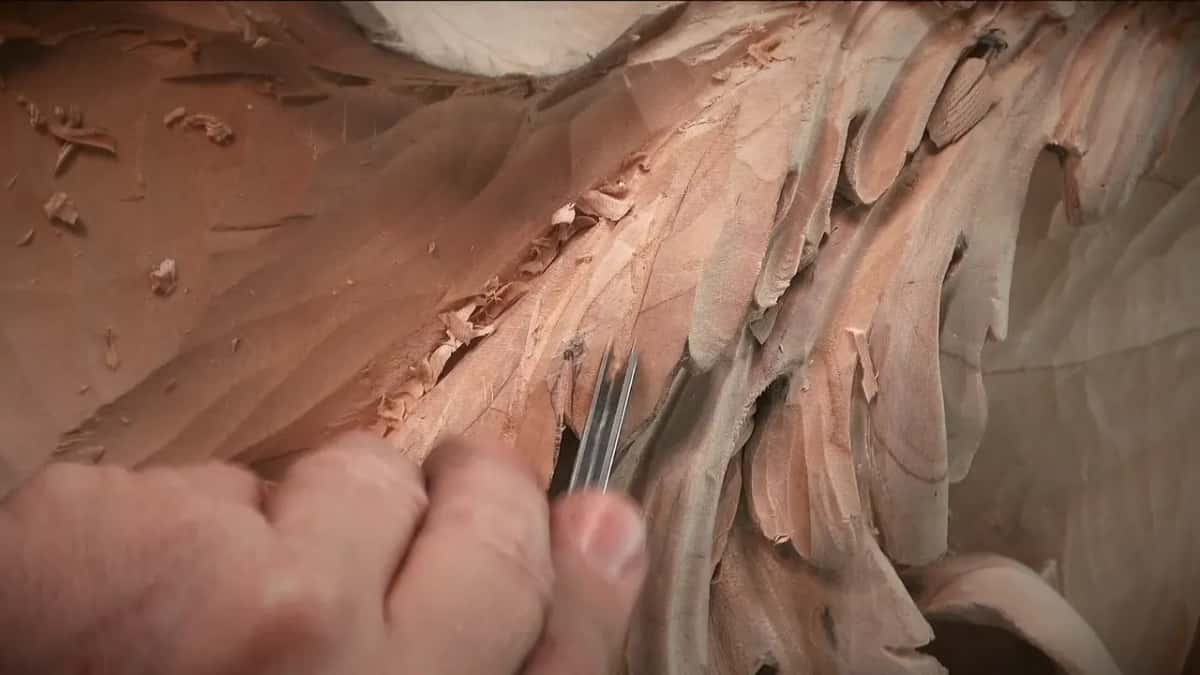 Fingertips pinch a narrow tool between long lobes.