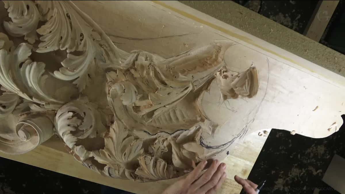 Left hand on the carved leaves, right hand holding a marker, and a flat part outlined beside them.