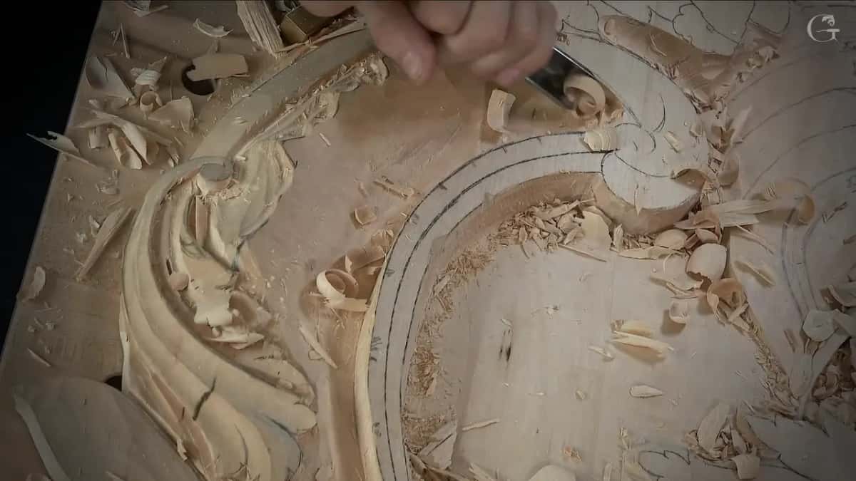 Chips cover the ground as a gouge works the top of the curved band