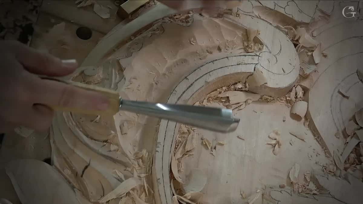 Long gouge held sideways above the hollow, shavings in the band below