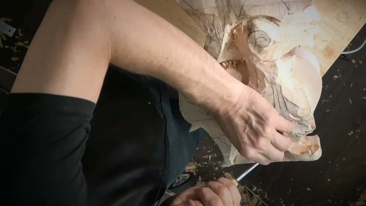 A forearm steers a bent tool through the middle of the leaf while chips pile up on the floor below