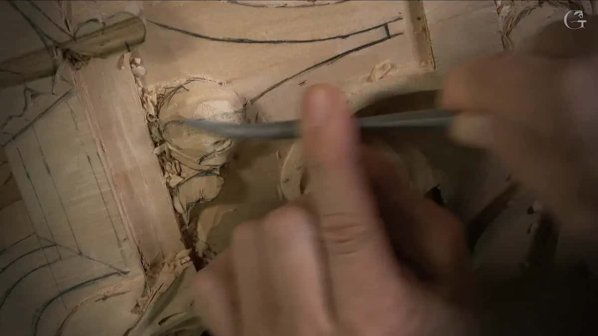 Thin steel tool rides over a rounded knob while two fingers guide it from the far side