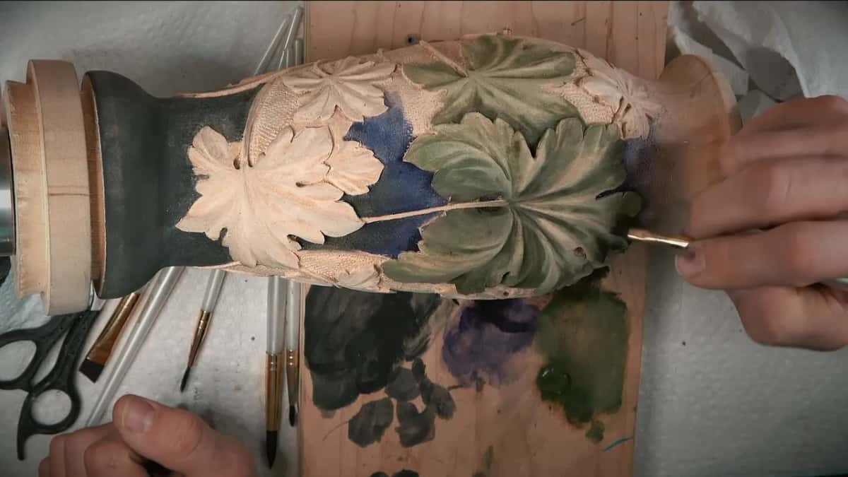 A brush reaches the tip of a leaf near the flared rim, with the black base at the far end