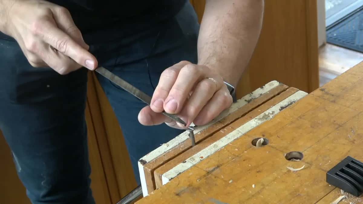 Flat file worked across the top of a nail standing upright in the bench vise