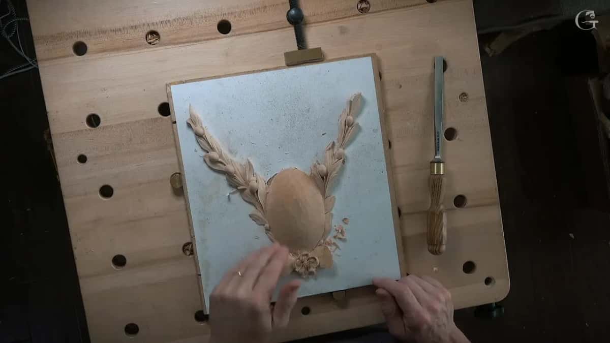 The whole rosette from above on the bench, both sprays carved, a gouge lying beside it