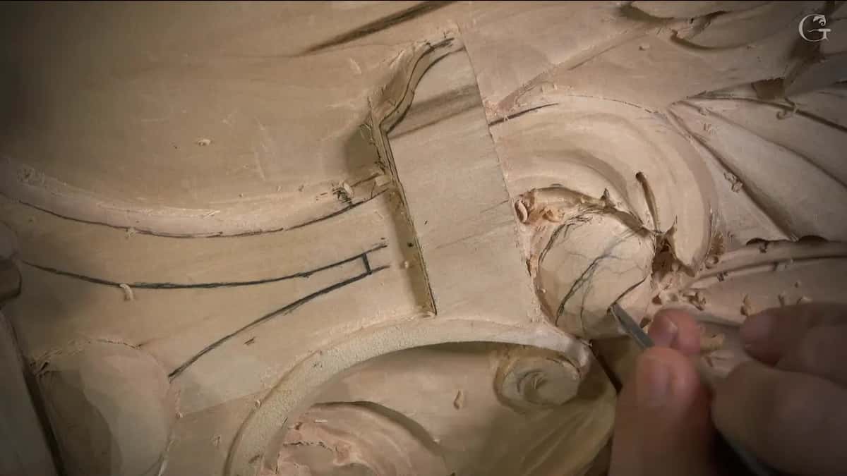 Tiny tool tip at the edge of the round eye, pencil lines drawn across it, fingers guiding from the lower right