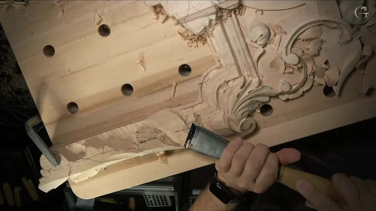 A broad, shiny gouge set against the lower edge, the scroll and flowers above it