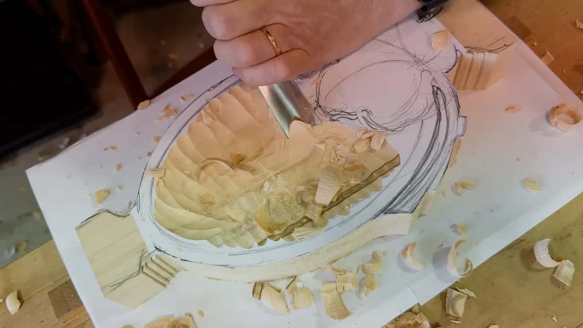 A hand with a ring holds the gouge at the far end of the dish