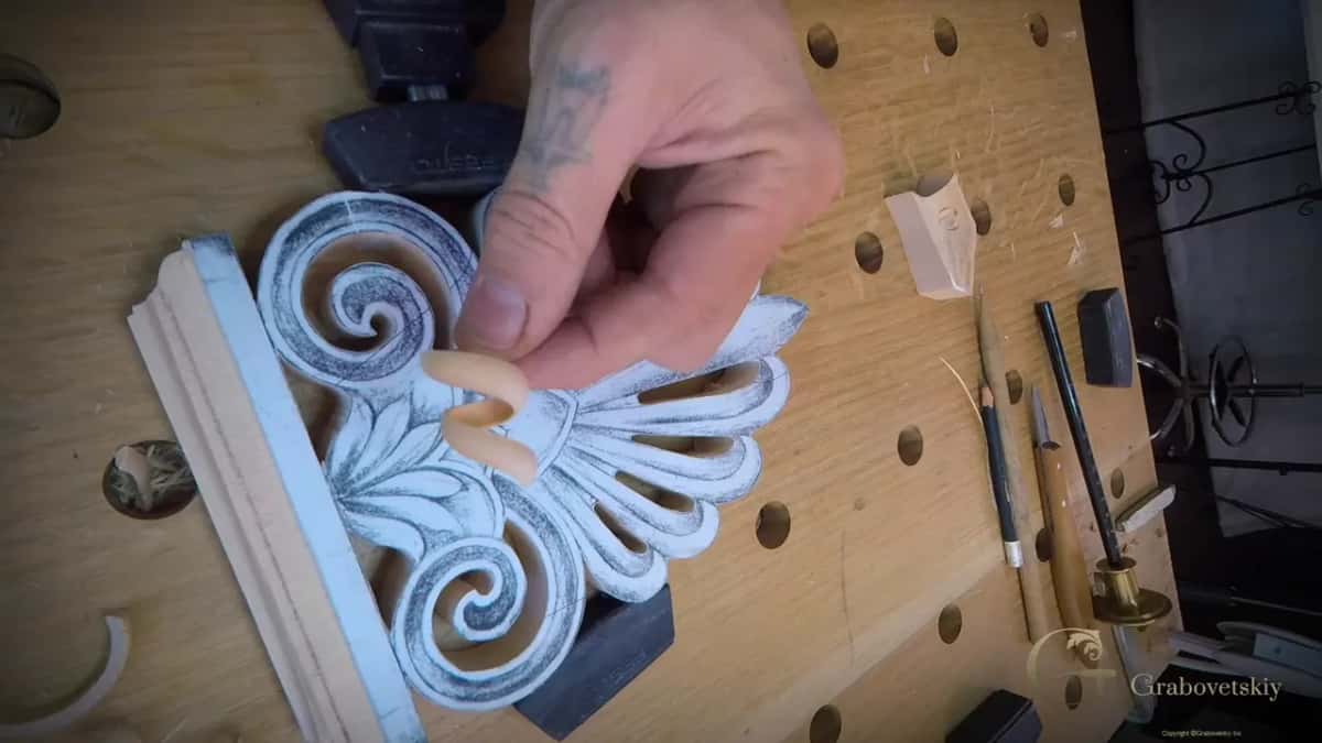 One clean curl held up between two fingers, the steps of the base sharp and pale beneath it