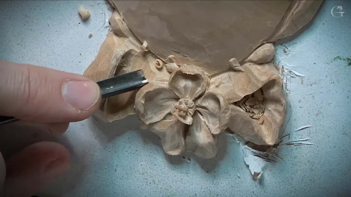 Fingers guide a narrow gouge sideways into the left loop while it hollows out