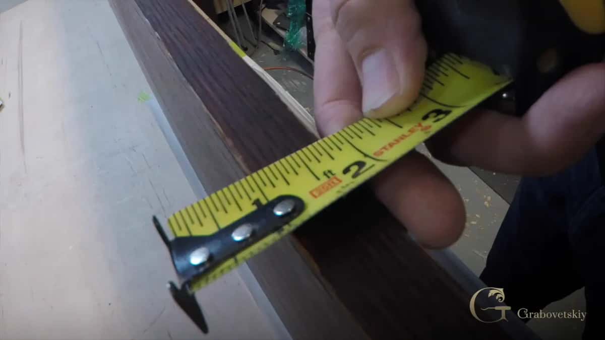 Yellow tape measure held against the edge of a dark board