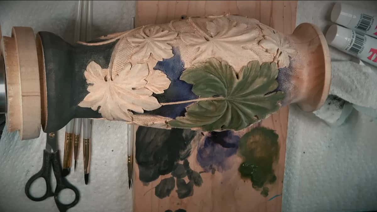 One leaf brushed green while the others stay bare above the black foot