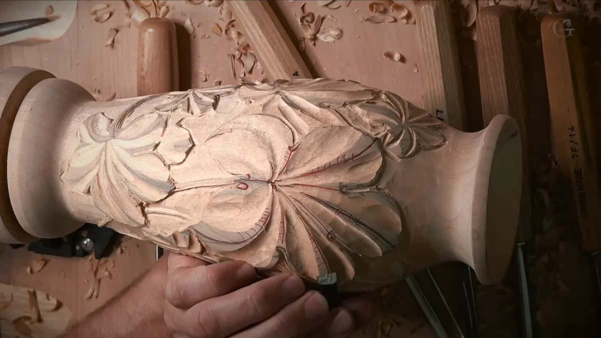 Hand working a gouge along the lower leaves