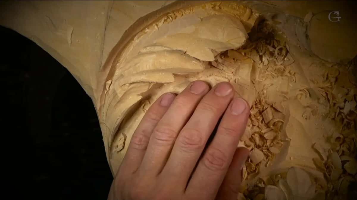 Fingers on a carved leaf curl.