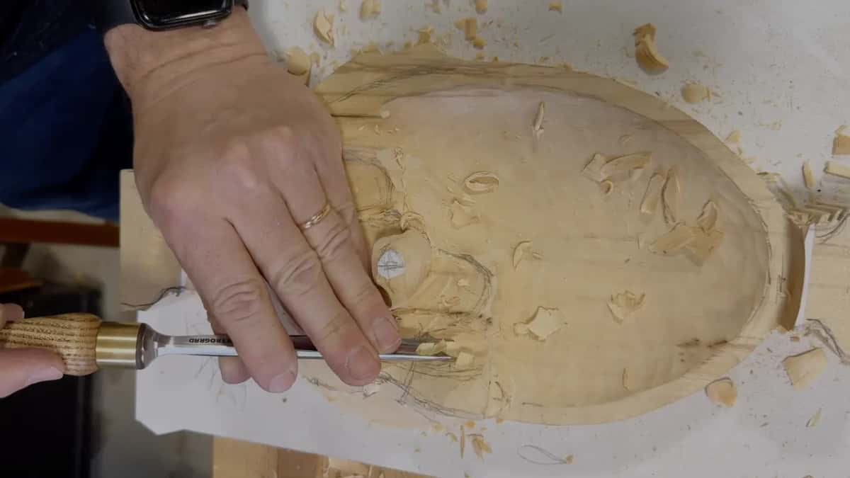 Palm flat on a long gouge as it works the lowest lobe, the hollowed bowl behind