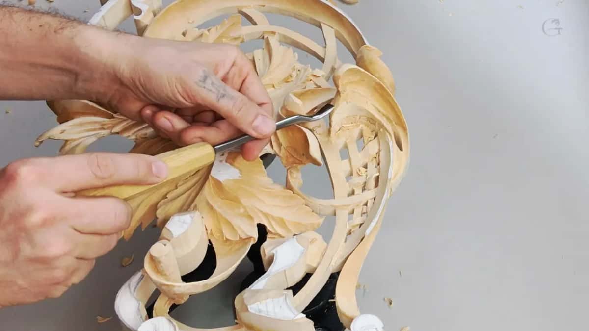 Fingers of both hands guide a bent tool under the curl of one leaf.