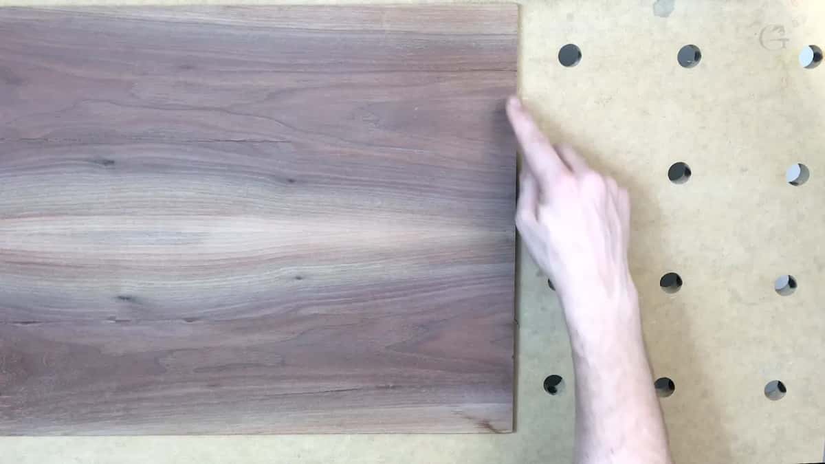 A finger touches the end of the board where it stops short of the pegboard holes.