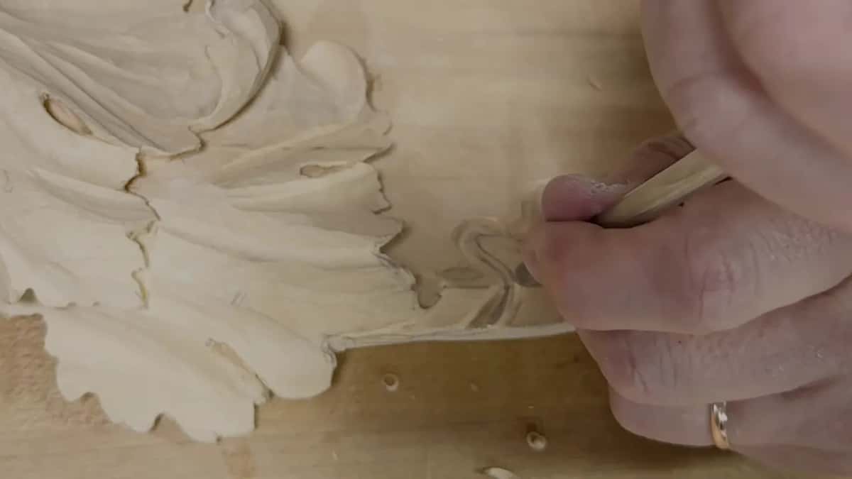 Closed fist on a wood handle, blade down in the curl beside the leaf