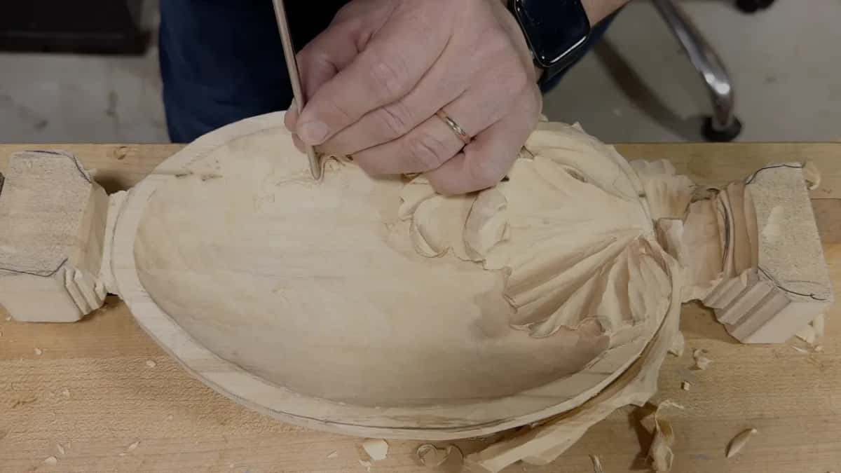 From the other end of the bench, a very thin tool works close to the rim while chips gather by the leaf