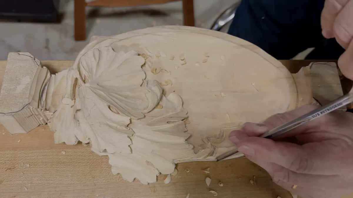Two hands guide a long slim tool along the lower side of the curl