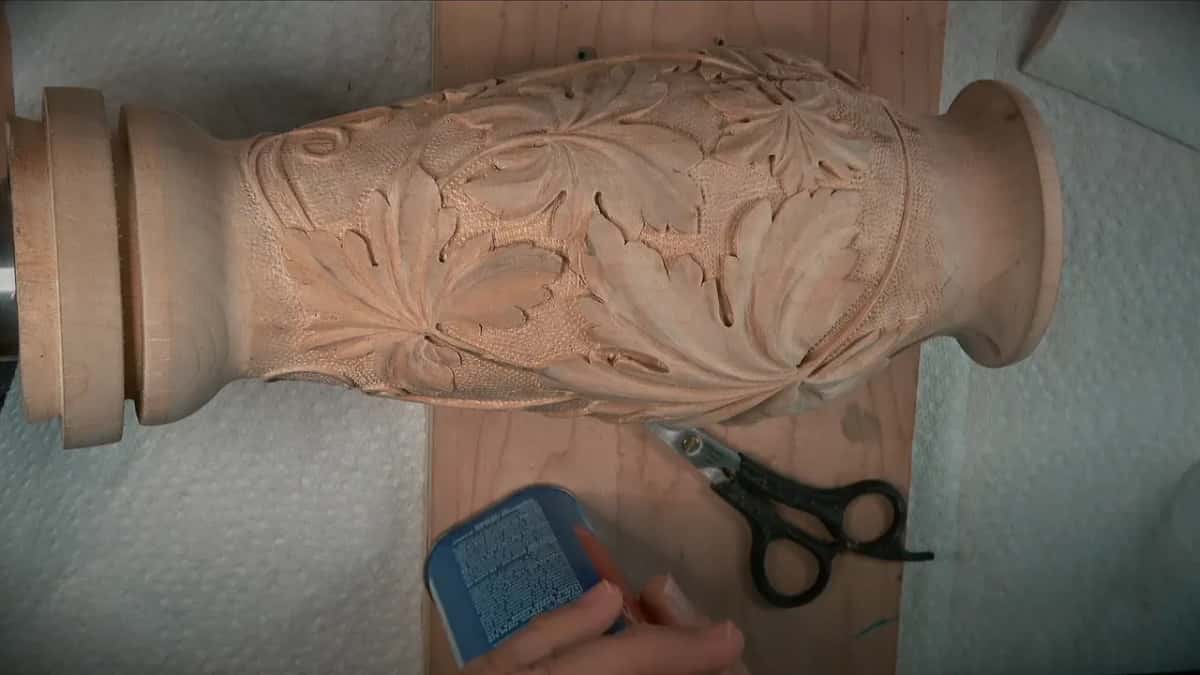 Carved vase on paper towels, a blue pad in hand