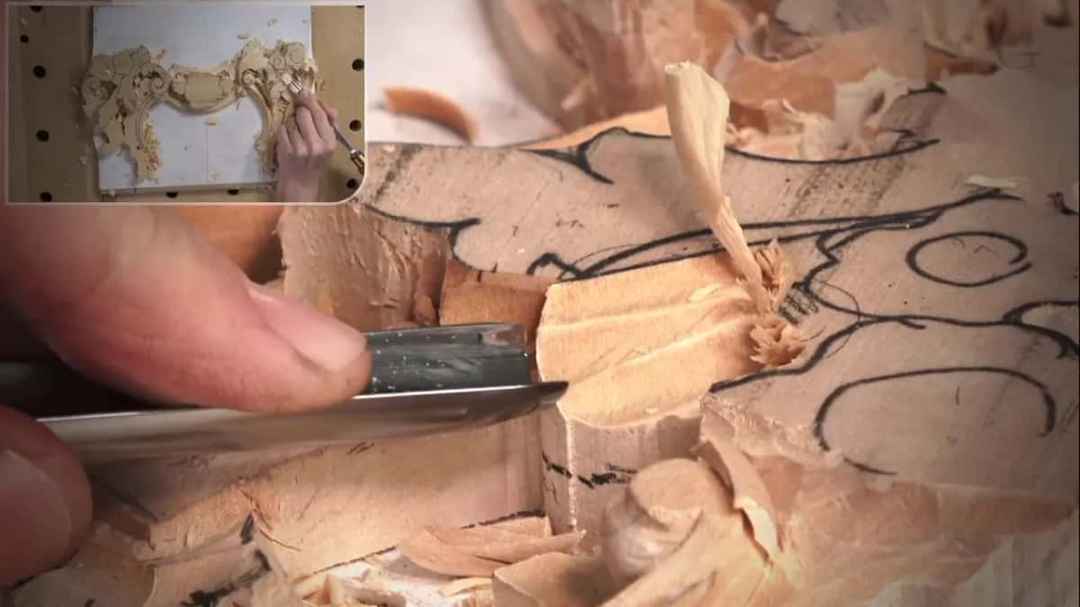 Thumb on a flat blade low in the wood as a thin shaving curls up from the pass