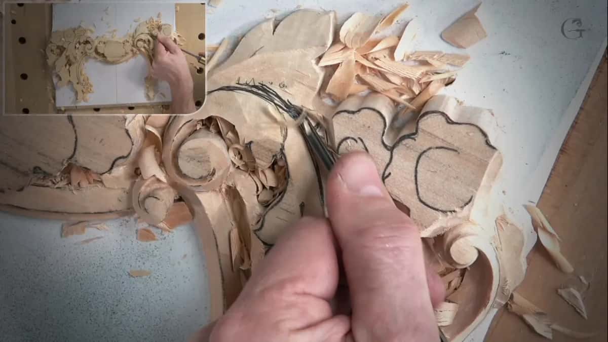 Narrow gouge following the inked line past a carved scroll