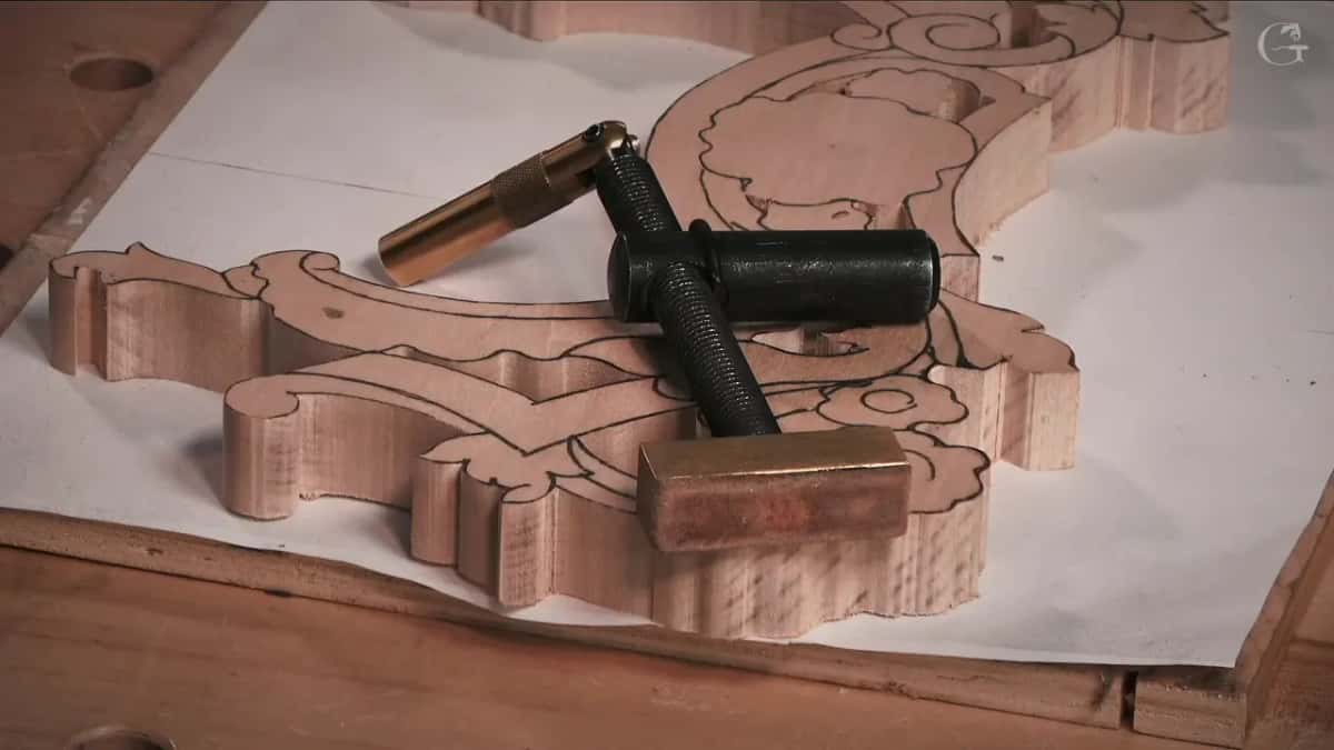 A brass and black bench clamp resting across the blank