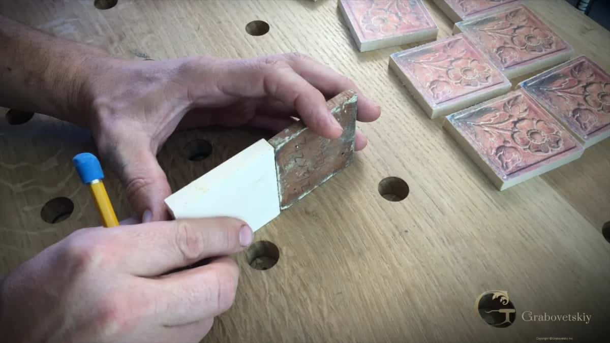 Dark original rosette pressed against a fresh block, a pencil in one hand and paper patterns waiting behind