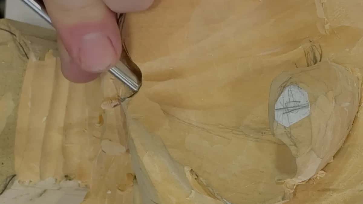 Chips lie scattered where a gouge works the edge beside the fluted end