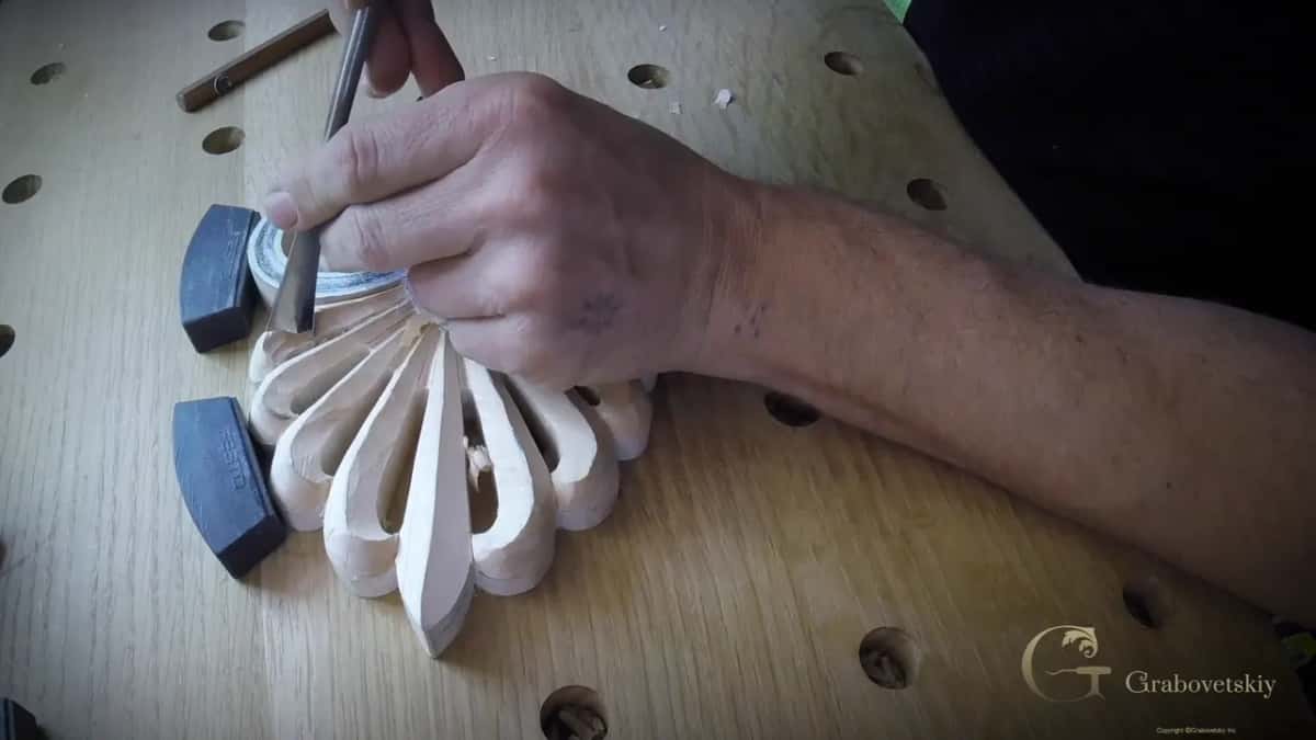 Hand over a gouge, its edge in a leaf next to the spiral