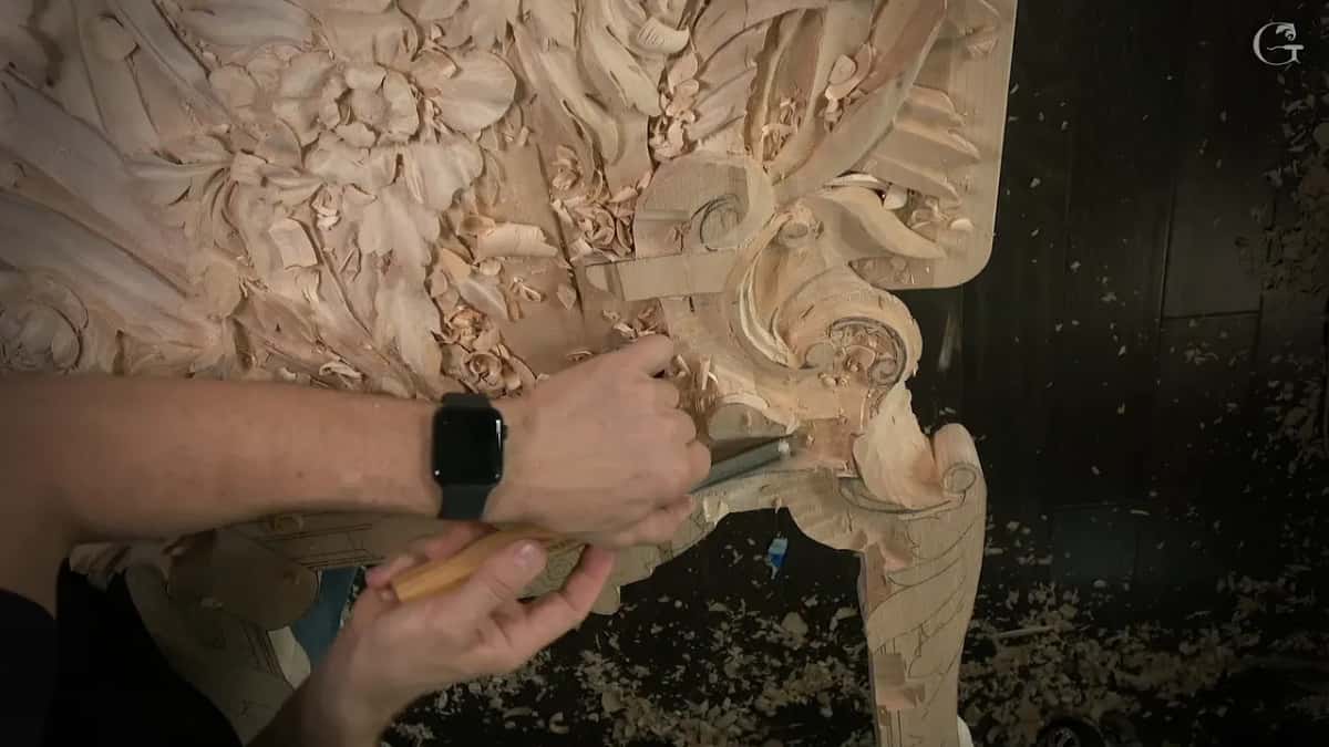 Hands push a gouge into the scroll