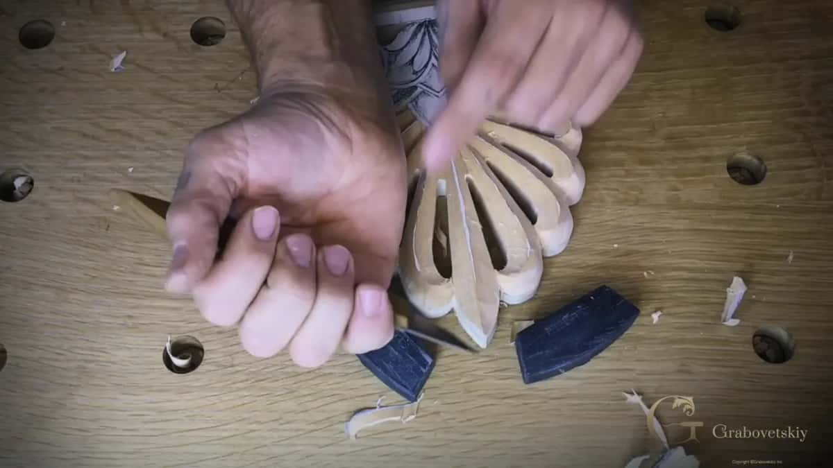 Knife gripped in a fist, slicing down the side of one petal of the fan