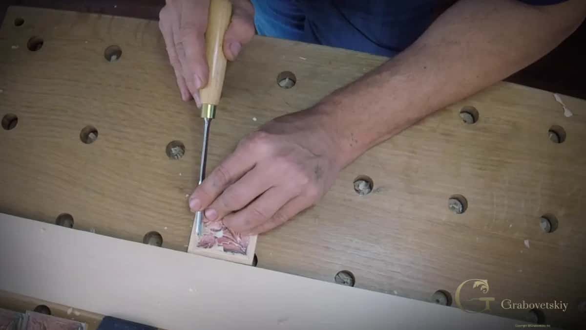 Held upright at the near edge of the block, on a bench full of holes