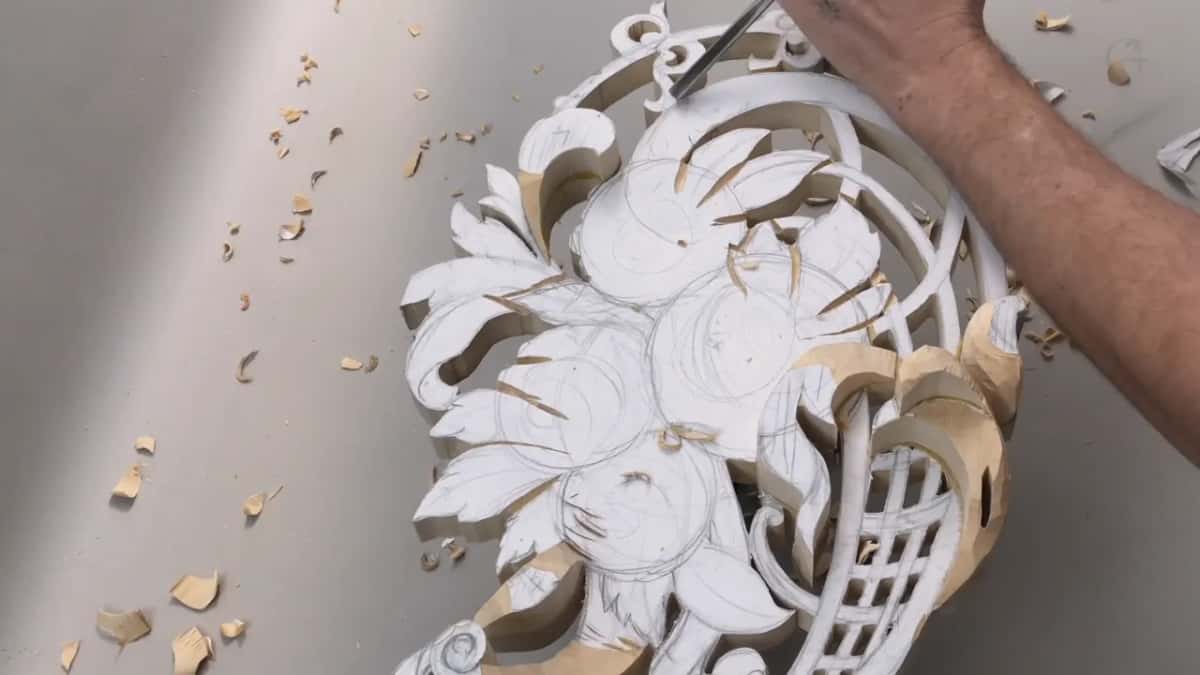 V tool held near drawn flower rings on the paper covered panel, basket lattice in the lower corner