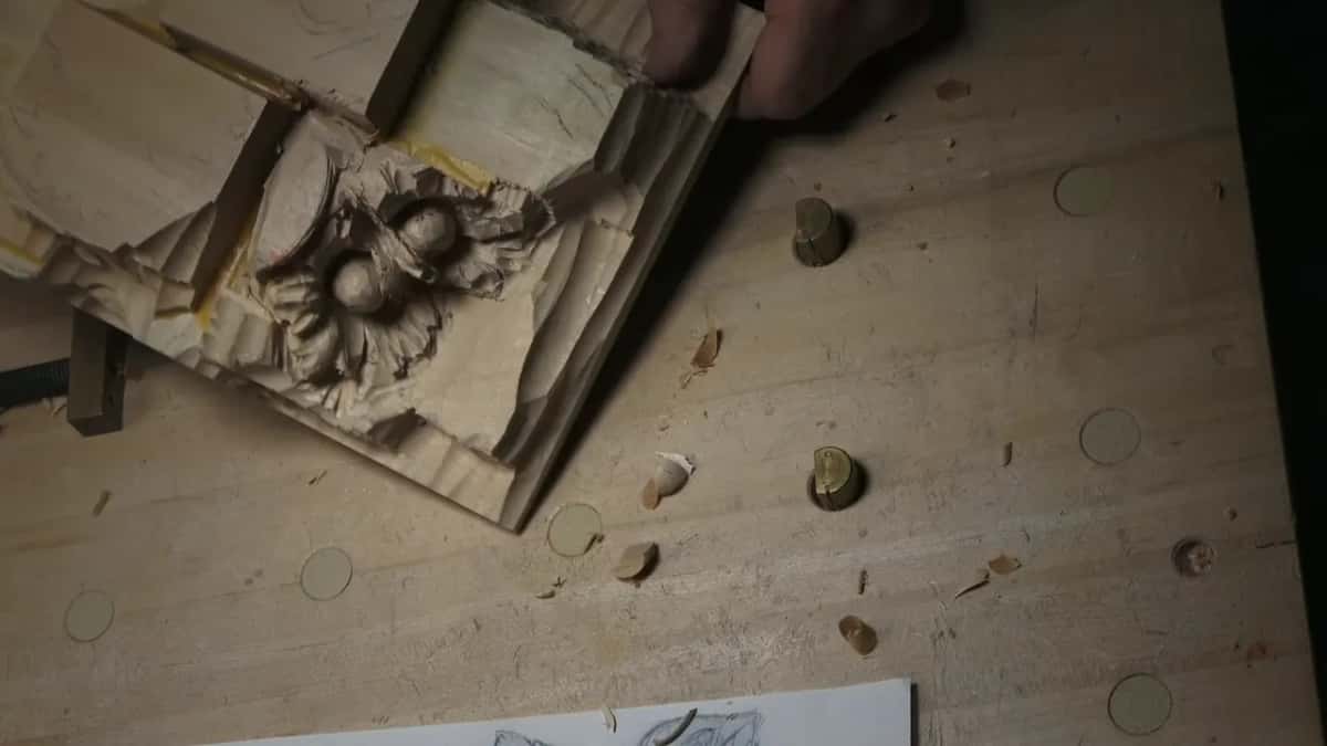 Seen from above, the whole carving rests on the bench next to round metal stops and a sheet of paper