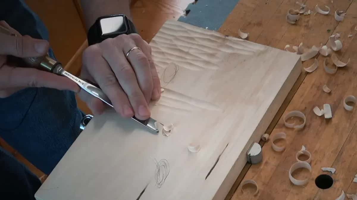 Rows of texture cover the upper half of the board as the gouge nears the bug