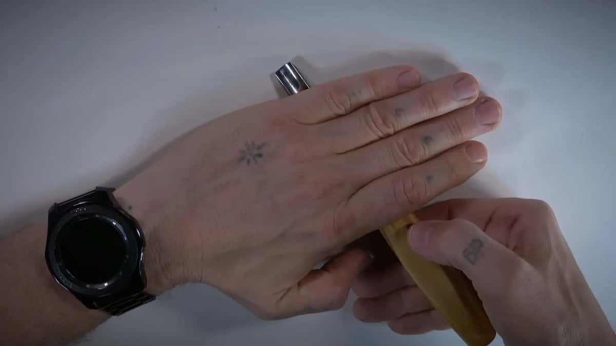 A left hand lies flat over a gouge while the right holds its handle, a chrome ferrule just showing