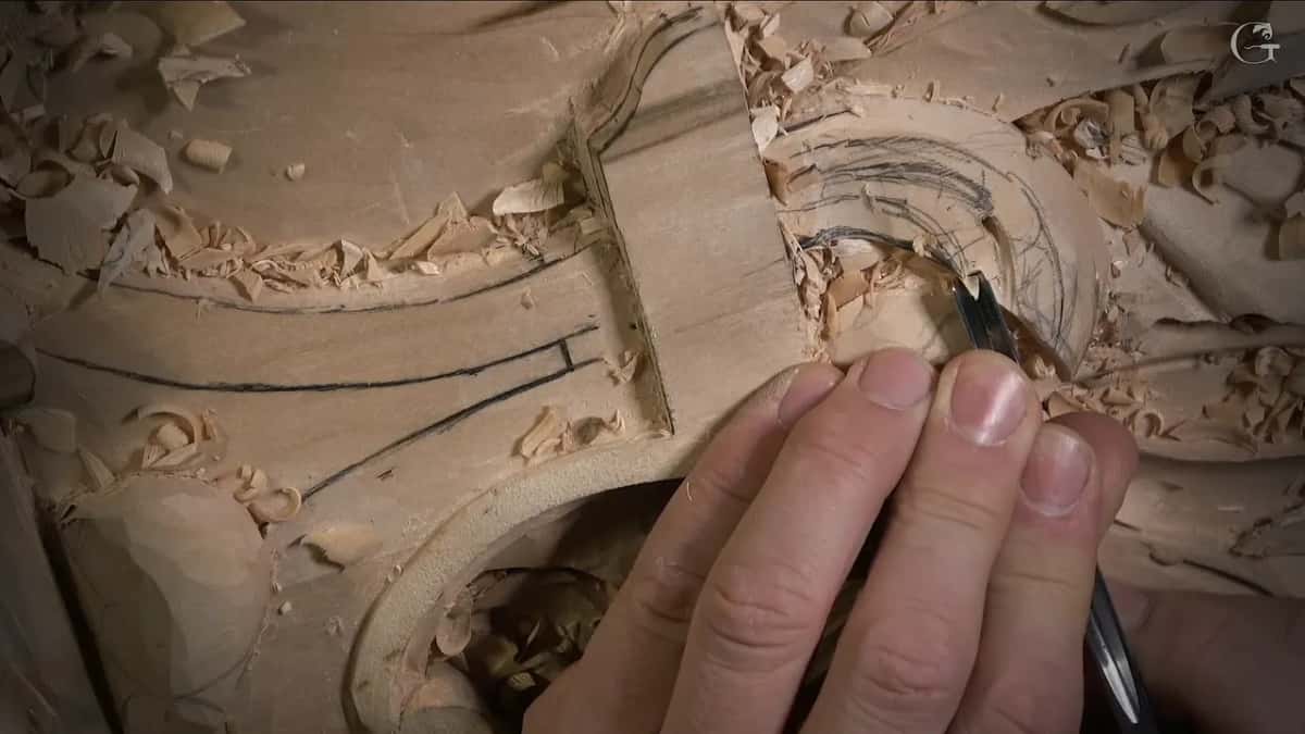 Fingertips press a narrow gouge along freshly drawn curves