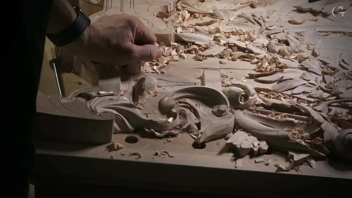 Low angle across the bench as a hand clears chips off the ornament