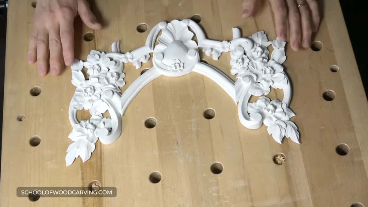 Both hands steady a white carved piece